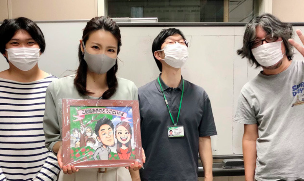 自身と夫のイラストをもつ石神愛子（左から2番目）